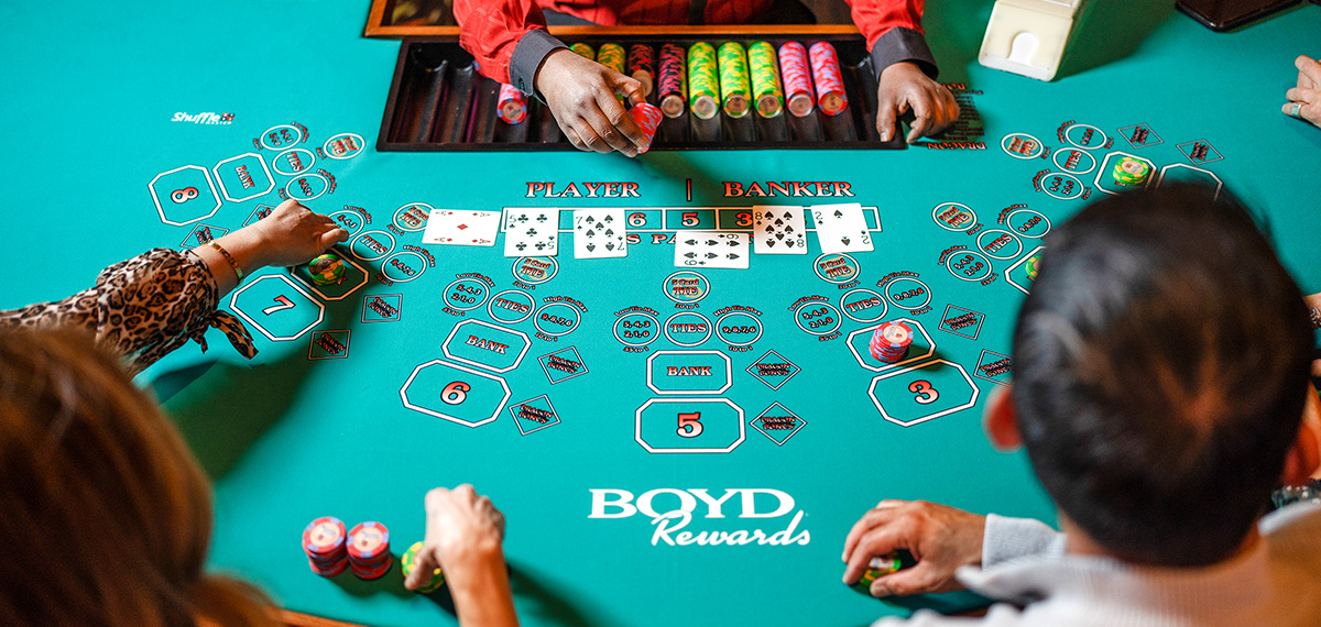 Couple playing baccarat from an above table view with dealer in a Boyd casino